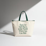 Beige tote bag with green text and handles on a light gray background