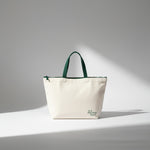 White tote bag with green handles on a gray background